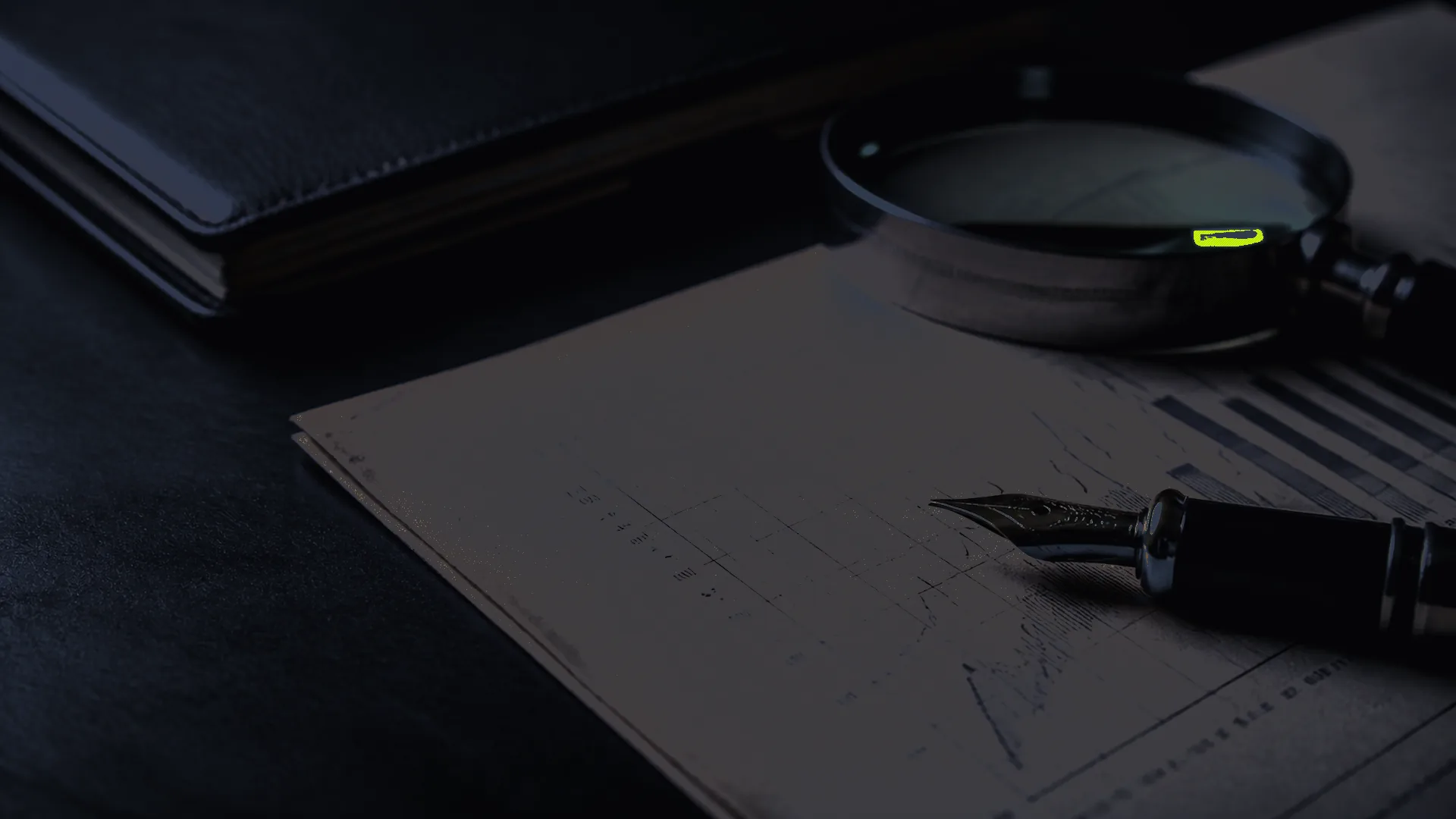 Macro still-life: an illegible printed graph on aged paper beside a fountain pen and a magnifying glass.